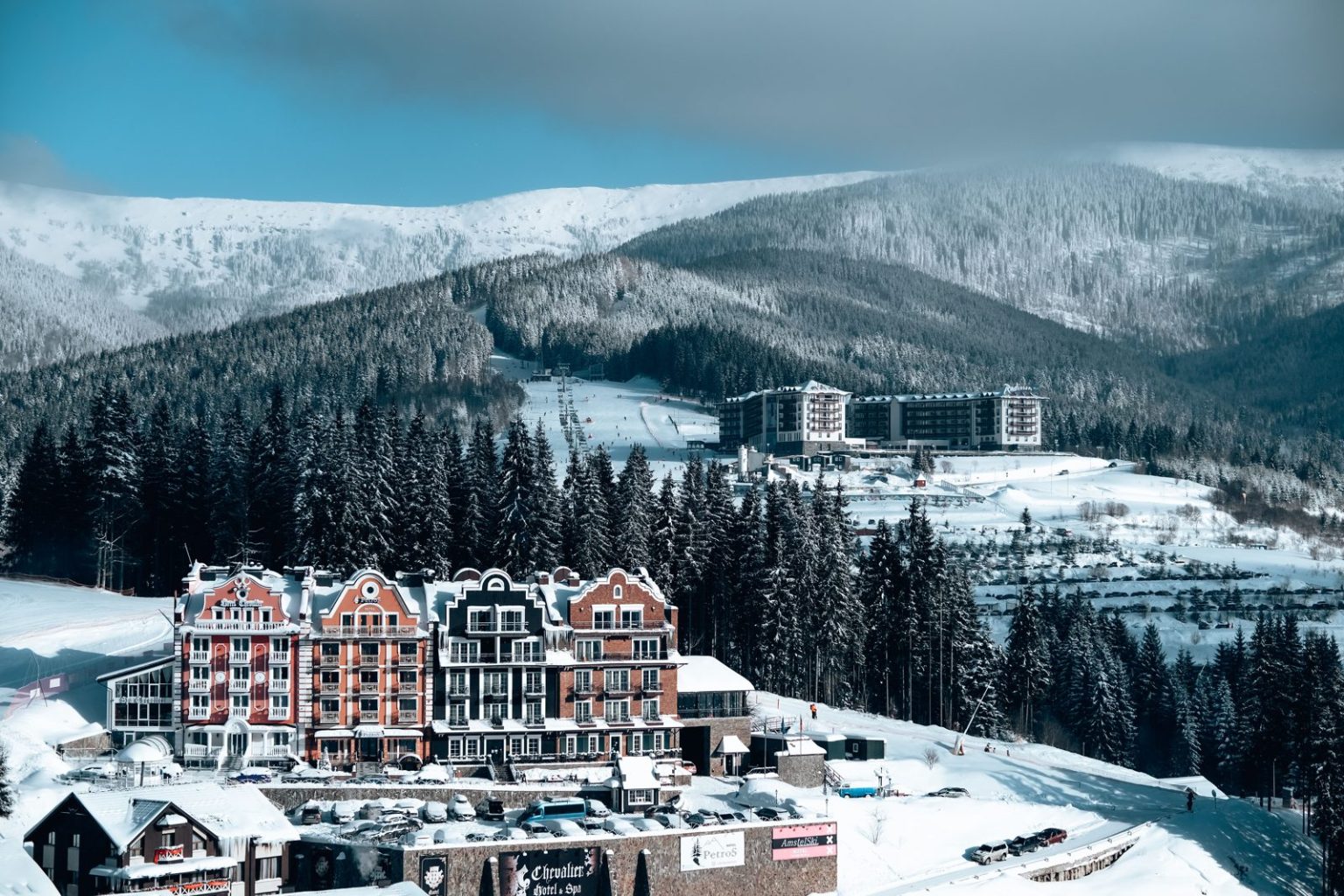 Hotel buildings in a snowy mountain landscape, illustrating ski-in ski-out apartments in the Alps